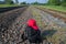 Black backpack with red cap on it next to railways on the background of long road`s perspective, trees and blue sky