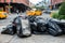 Black bags of trash on sidewalk in New York City street waiting for service trash truck. Garbage packed in big trash bags ready