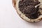 Black barley grains on ceramic plate over white wooden background