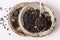 Black barley grains on ceramic plates over wooden background