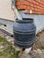 A black barrel for sewage is attached to the house by the gutter