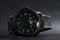 A black battery operated watch on black leather background