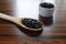 Black beans. Wooden spoon with black beans and portion of beans in ramekin on wooden table in backlight.