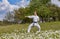 With a black belt, an athlete strikes with a hand while standing on the green grass