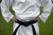 Black belt in karate. Hands on the belt. White kimono. Place for text.