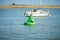 A black bird sitting on a water buoy. Green marker buoy floating in the sea. seagull, beacon. Sunny day summer.