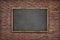 Black blank blackboard with wooden frame on brick