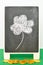 A black board with a four leaf clover and a heap of golden coins