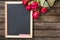 Black board and red roses on wooden background, top view