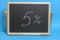 Black Board in a wooden frame on a blue background with the inscription 5 percent. Mockup for shopping, sales