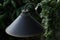 Black bollard light in green fresh leaves of tree