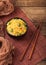 Black bowl with boiled organic basmati vegetable rice with wooden chopsticks on brown placemat with linen towel. Yellow corn and