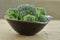 Black bowl with cuts broccoli on wooden background