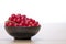 Black bowl with redcurrants on a wood table