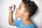 A black Boy using an asthma inhaler