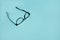 A black broken eyeglasses on blue background.