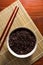 Black brow rice in bowl with chopstick.