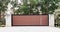 Black brown metal wrought iron driveway property entrance gates set in concrete brick fence, lights, eucalyptus garden trees in ba