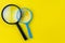 Black and bue magnifying glass, magnifier on yellow background with copy space using as search, transparent, science discovery or