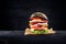 Black burger with egg and bacon on black wooden table