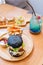 Black burger with meat patty, cheese, tomatoes, mayonnaise, french fries in a paper cup and glass of cold cola soda with ice.