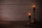 Black burning candles in candlesticks on old wooden background
