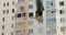 Black burnt window of an apartment in a high-rise building. Air conditioners hang on the walls. Yellow-blue building.