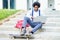 Black businessman with afro hair and skateboard using his laptop computer sitting on some steps.