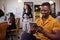 A Black businessman scrolls on his tablet in a busy diverse office