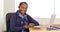 A black businesswoman poses for a portrait at her desk