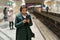 Black businesswoman wait at subway platform for train reading text or business email on smartphone