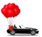 Black cabriolet car with bunch of red helium heart balloons
