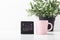 Black calendar with pink mug and plant in pot