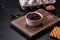 Black, canned beans in a white saucer against a dark concrete background