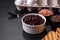 Black, canned beans in a white saucer against a dark concrete background