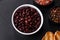 Black, canned beans in a white saucer against a dark concrete background