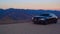 Black car Audi A6 with driving on mountains road during sunset and mountains in background low light shot. Highway in the mountain