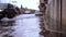 Black car drives along asphalt road covered with high water