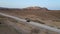 Black car driving on asphalt road through the desert sands