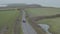 Black car speeding on a country road surrounded by green fields, on a