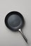 Black cast iron frying grill pan with glossy steel handle on gray background. Cooking food preparation cookware kitchenware