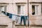 A black cat sits in a window. Clothes are dried on a clothesline between the windows.