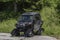 Black caterpillar snow car on asphalt road in summer hot day