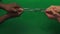 Black and Caucasian male hands are pulling iron chain on green screen in closeup