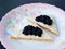 Black caviar on bread slices on colorful plate over black slate