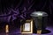 Black cemetery urn with blank golden mourning frame and dark green ribbon on deep purple background