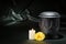 Black cemetery urn with churning candle yellow rose on dark green background