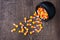 Black ceramic cauldron filled with holiday candy corn tipped over on a rustic wood background, spilling over onto the background