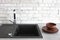 Black ceramic sink with mixer on a background of white bricks with clay bowls, Scandinavian style