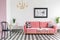 Black chair and pink settee with pillows in white living room in